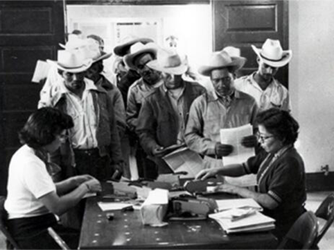 Image of Temporary clerks receiving typed forms I-100(a) and (b) (micas) were then presented to clerks who stapled photographs to the cards. Rio Vista Reception Center, El Paso, Texas.