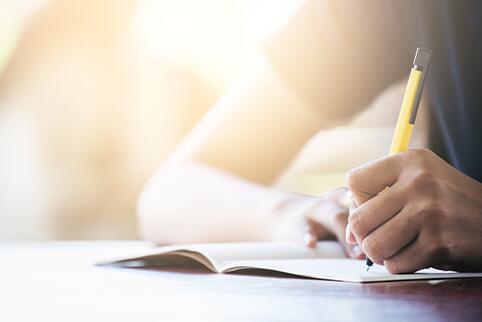 Person's arm writing in a notebook at a table
