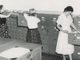 Historical photo of clerks in a immigration file room.